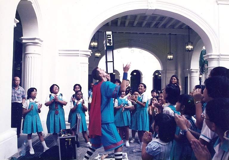 Ben balancing a stack of cigar boxes on his chin for a crowd of schoolchildren at a museum show.