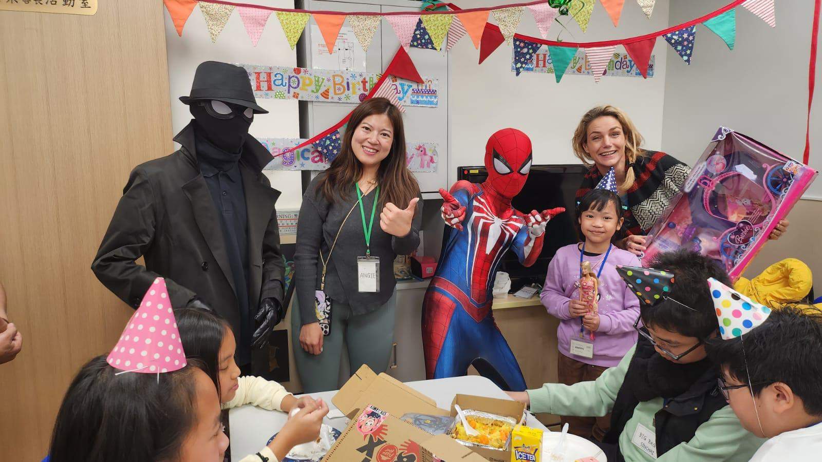 Adults and costumed performers pose with a child holding a toy.