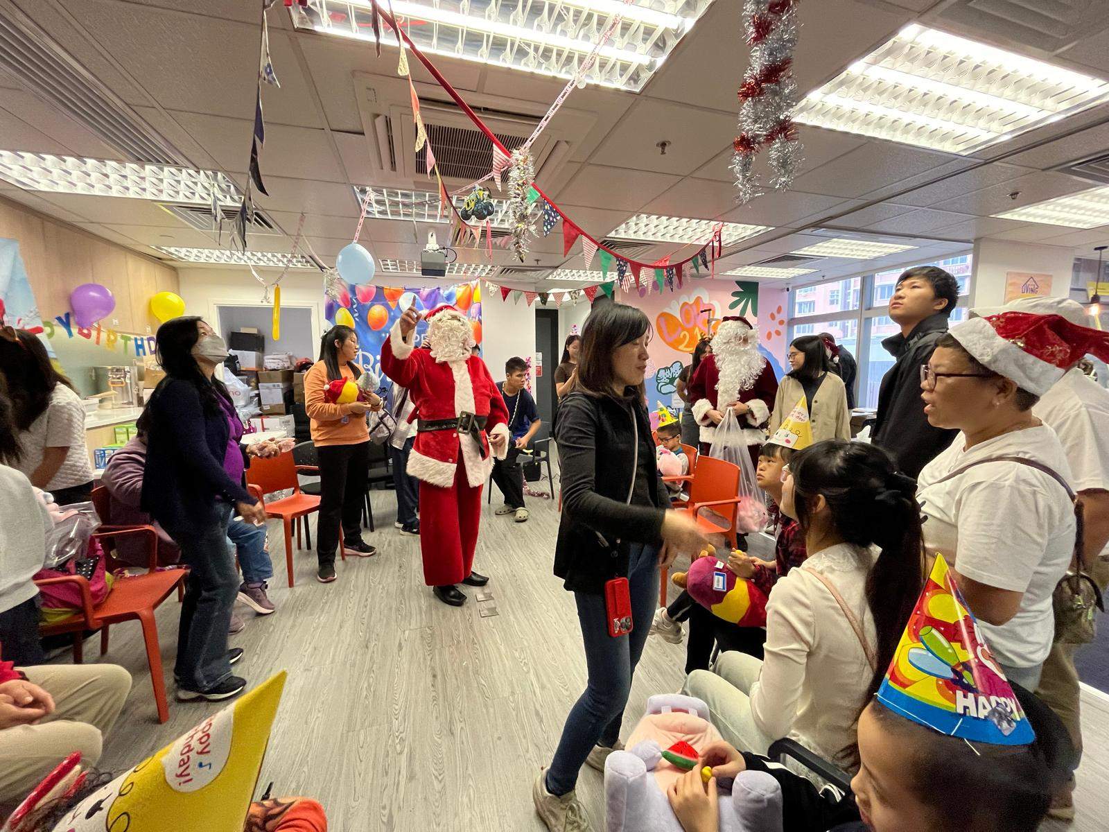 People gather around a standing costumed adult during gift distribution.