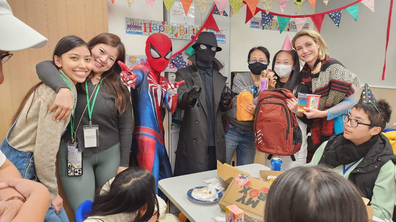 Adults and costumed performers pose together behind a table.