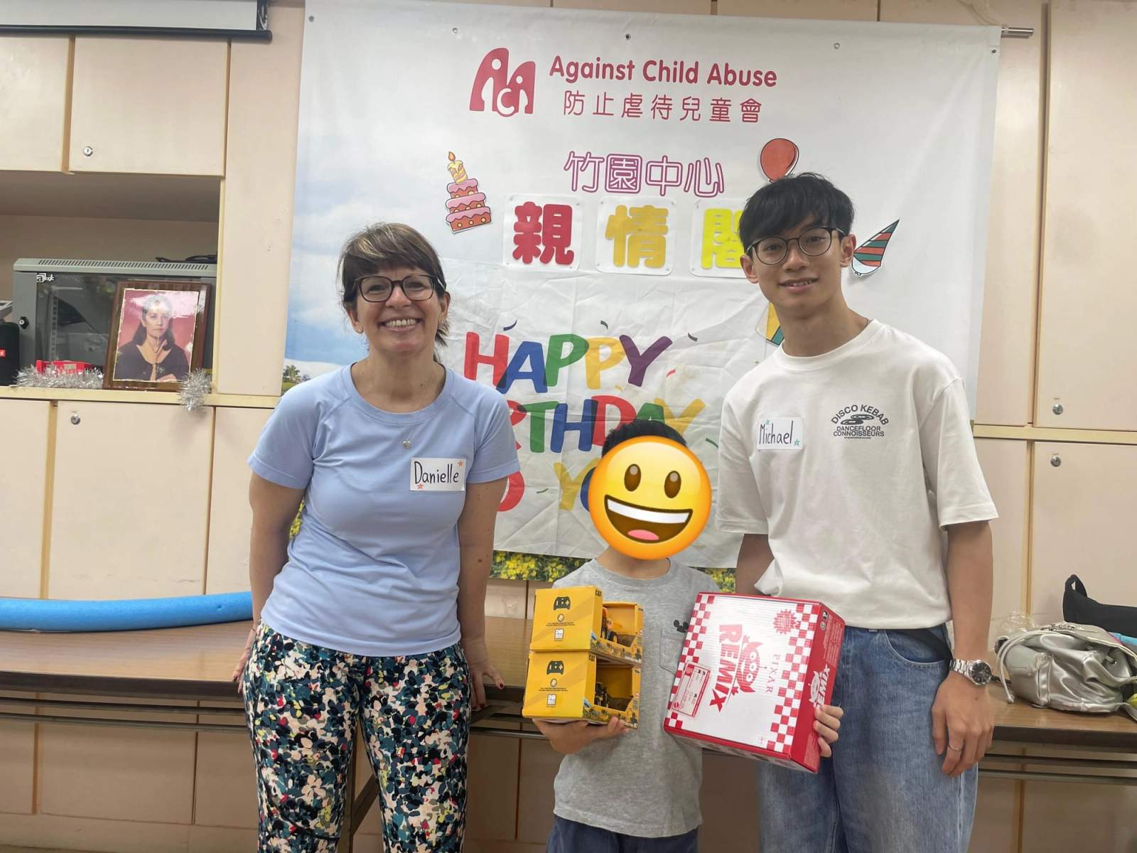 Two adults pose beside a child holding boxed gifts.