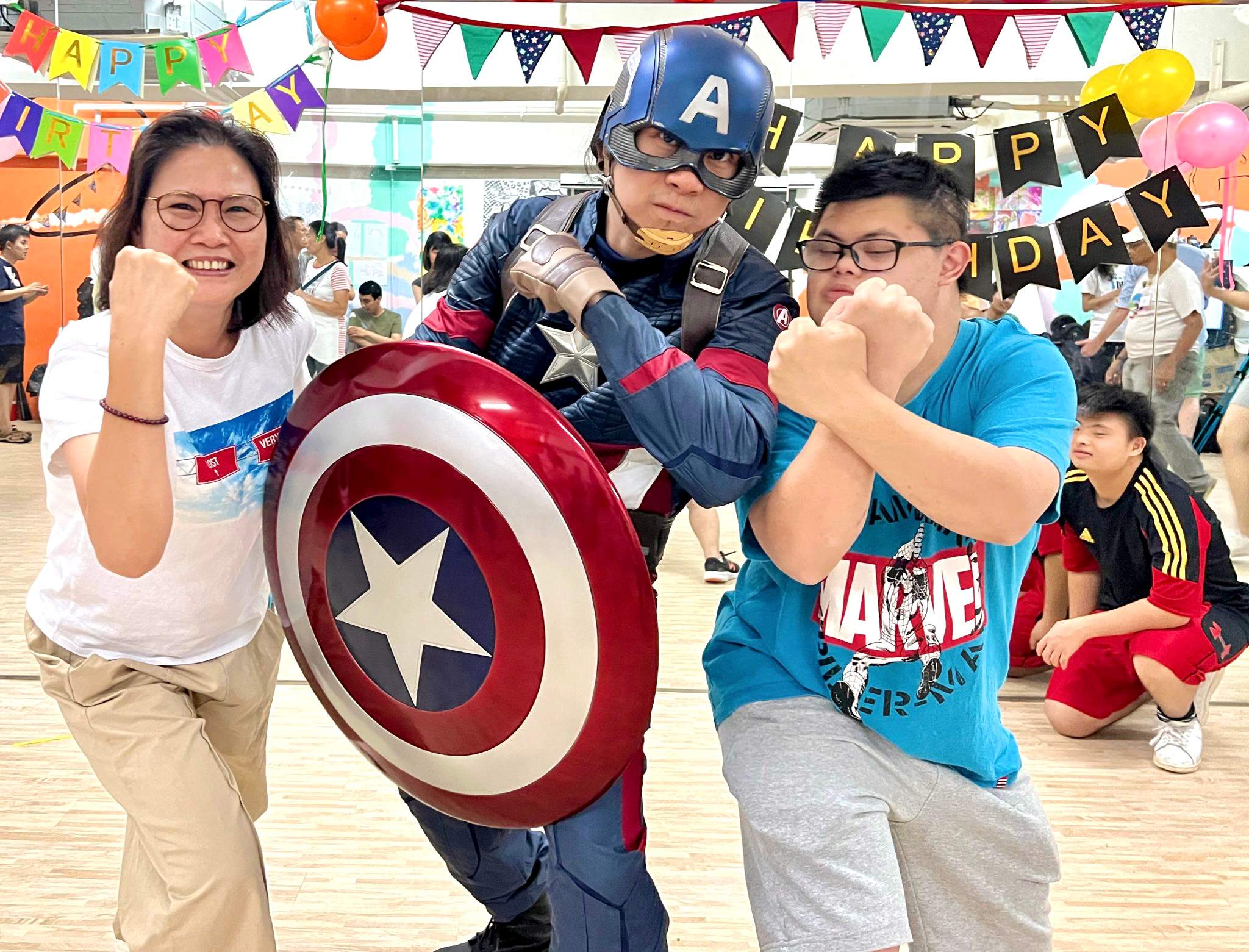 Kiryu Chan as Captain America, striking a pose with a birthday celebrant and his family at a party.