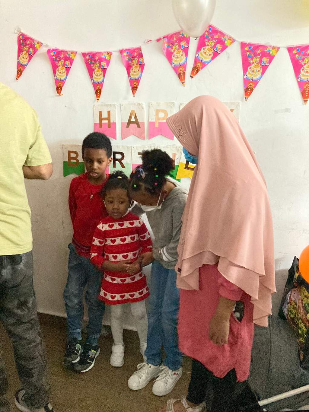 Children and an adult pose together beneath colourful bunting.