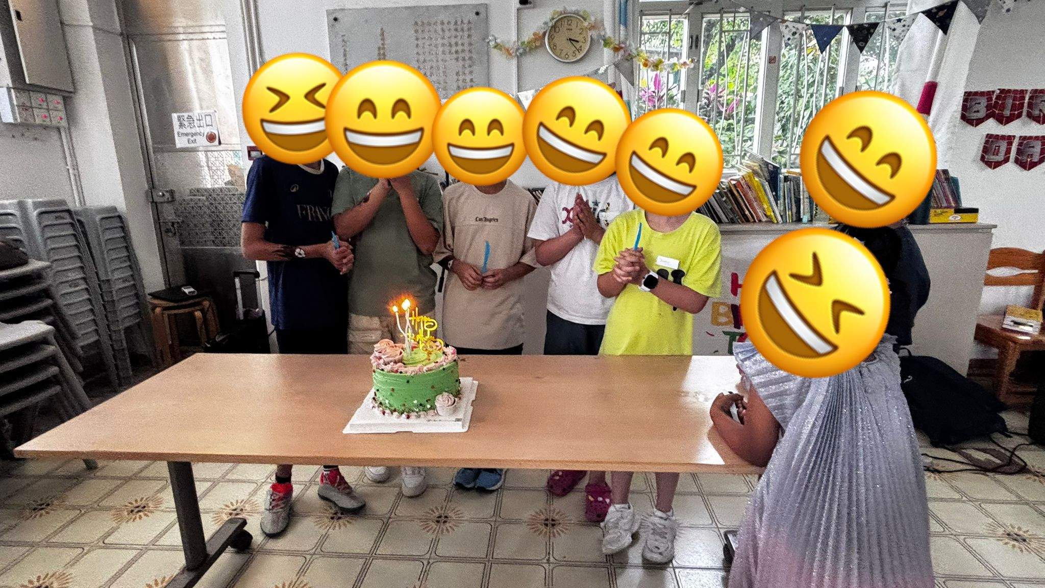 Children and adults gather behind a cake with lit candles.
