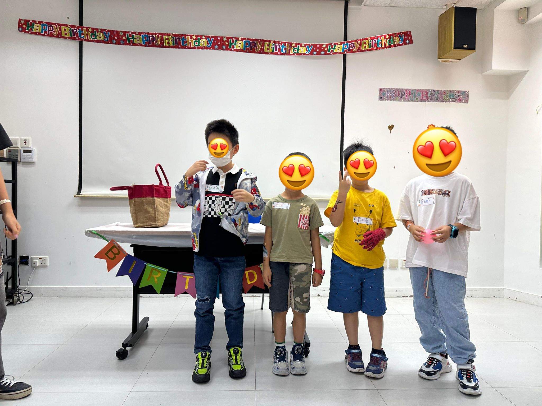 Four children stand together holding several colourful party gifts.