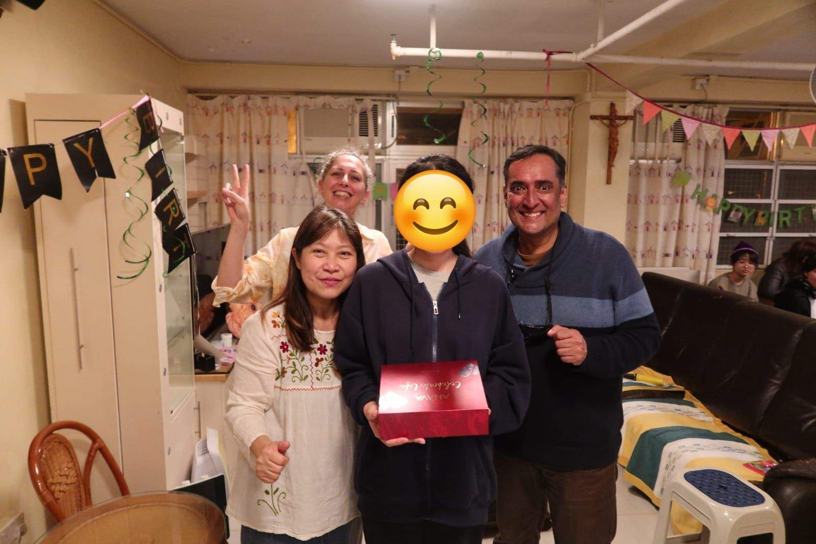 Three adults pose together with a boxed gift.
