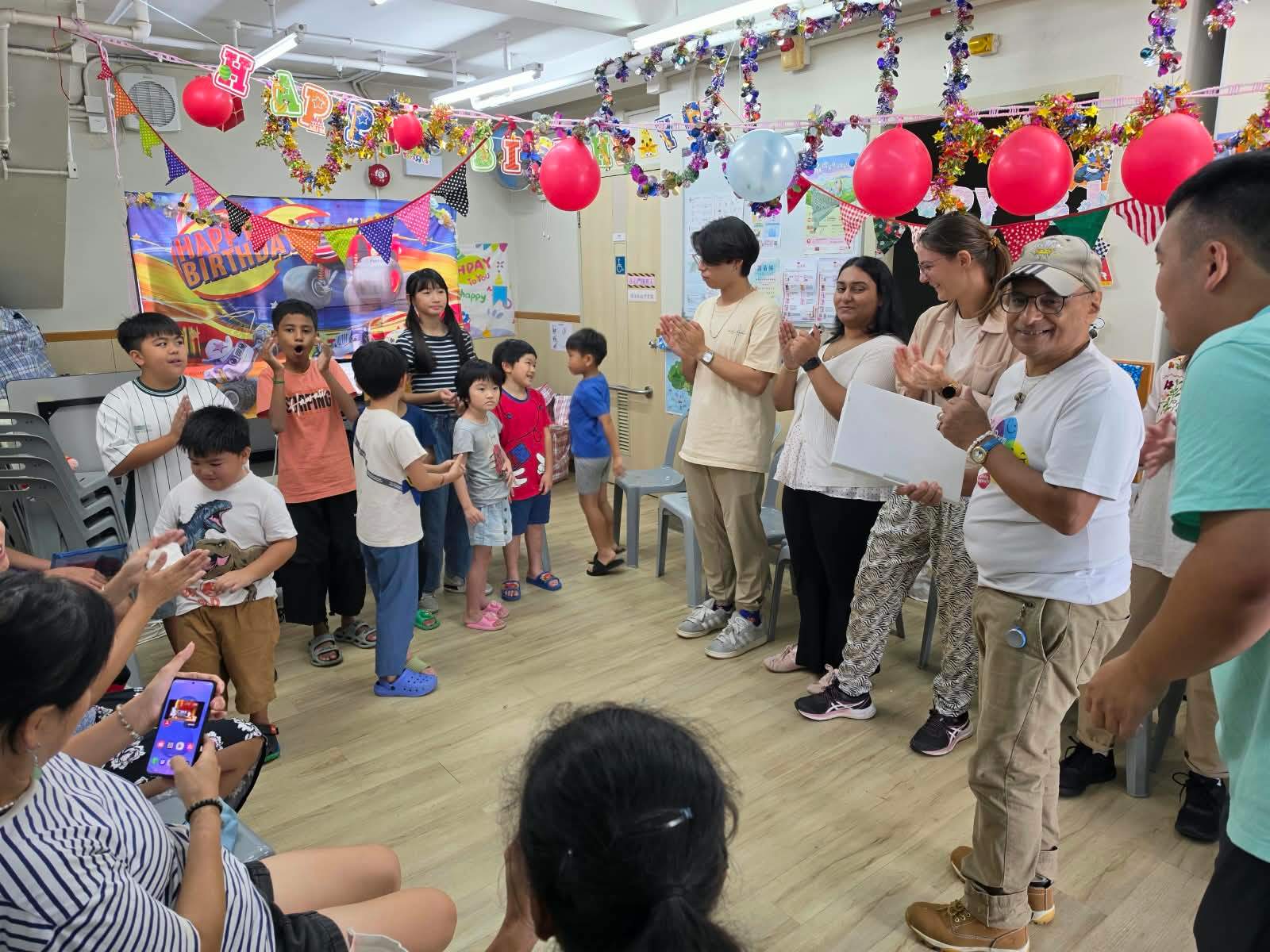 Children and volunteers applaud together at the end of the party.
