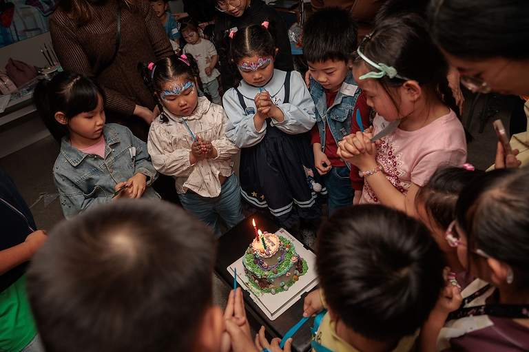 Children gather closely around a small decorated cake.