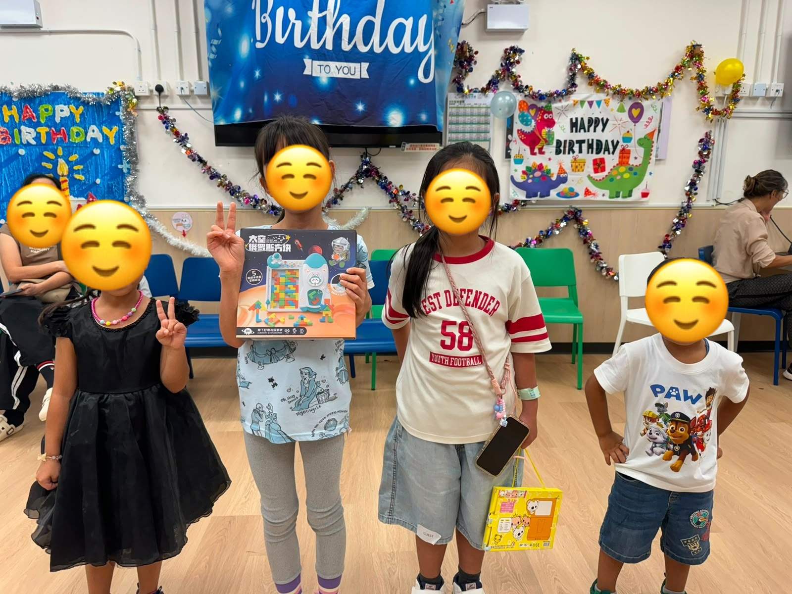 Children stand together while holding birthday gifts.