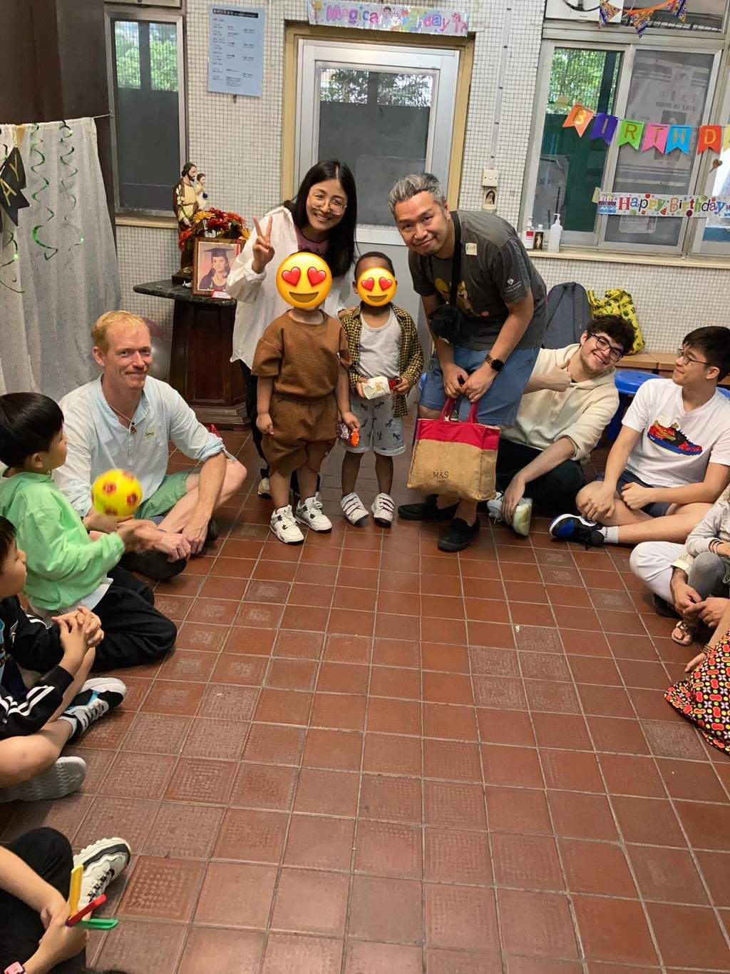 Adults pose behind three children in the centre of a circle.