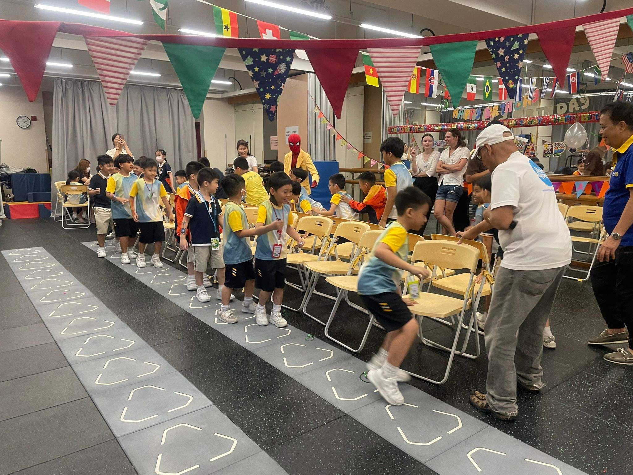 Children queue for a game involving rows of chairs.