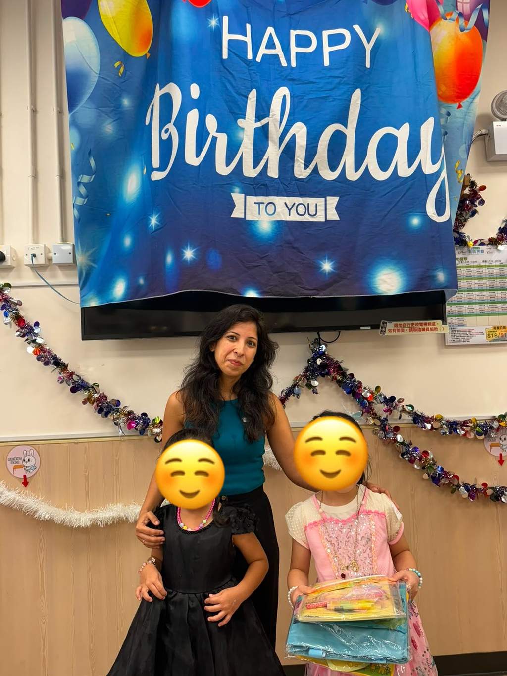 An adult and two children pose before the birthday backdrop.