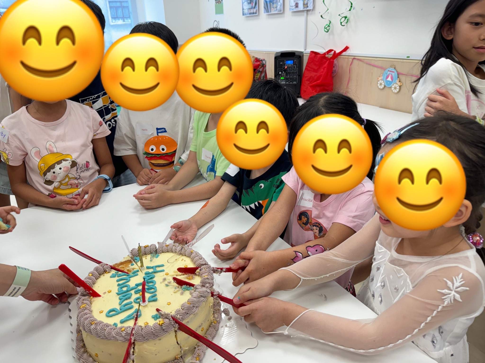 Children gather around a cake while holding red candles.