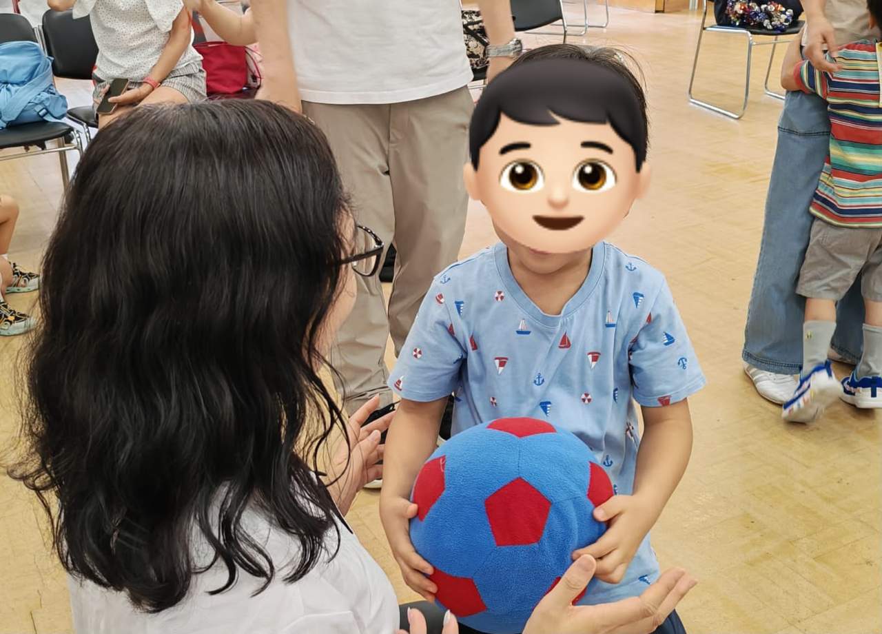 A child holds a large red ball during an indoor game.