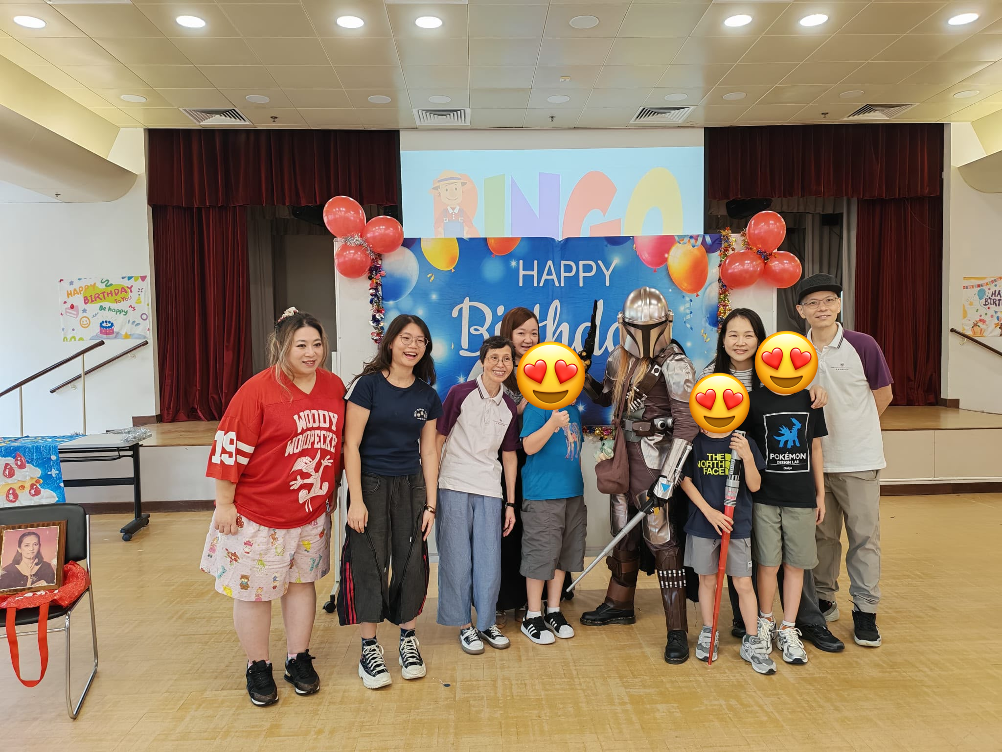 Children and adults pose with an armored character before party decorations.