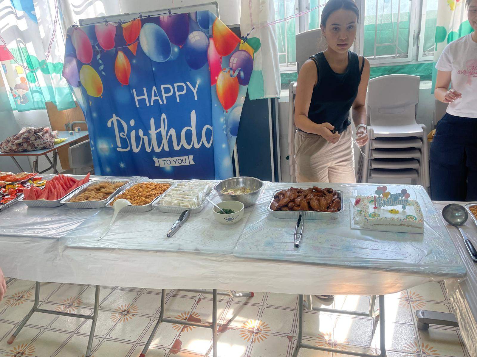 Trays of food are arranged beneath a balloon backdrop.