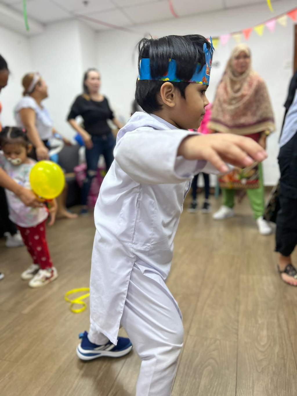 A blindfolded child reaches forward while adults and children watch.