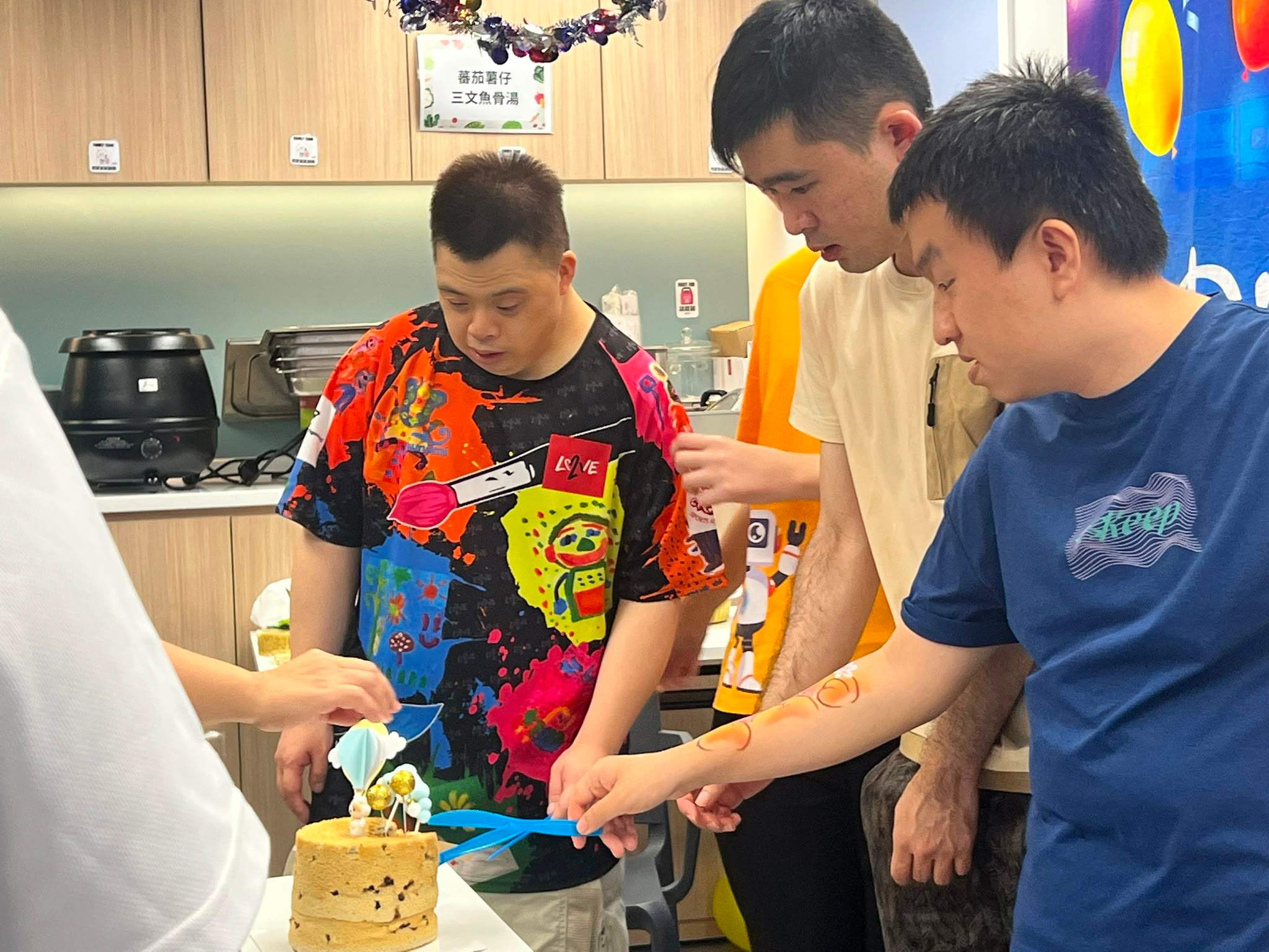 Three people cut a decorated cake at a table.