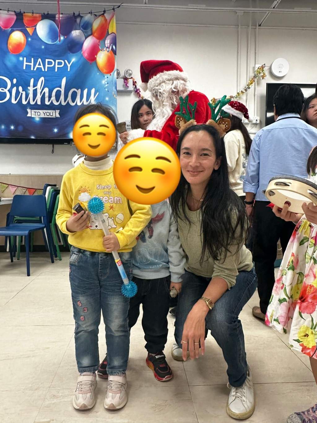 Two adults crouch beside a child holding a stuffed toy.