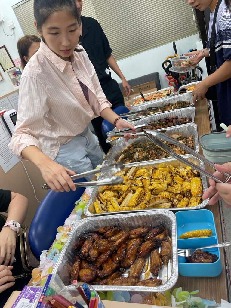 An adult serves food from trays arranged along a table.