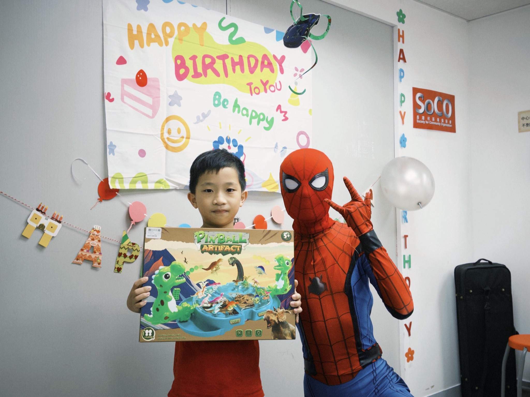 A child and costumed performer pose with a boxed gift.