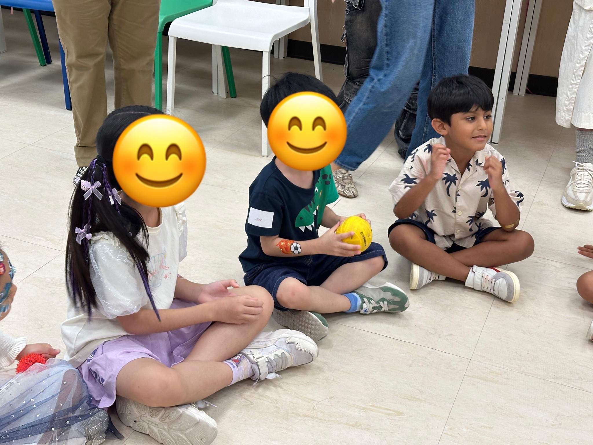 Children sit on the floor holding small colourful balls.