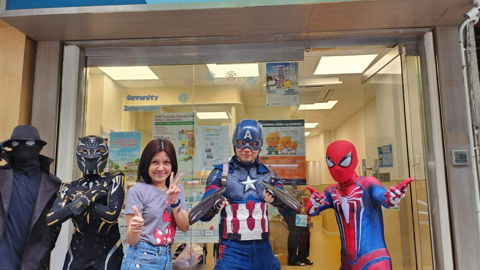 Costumed performers and an adult pose together near glass doors.