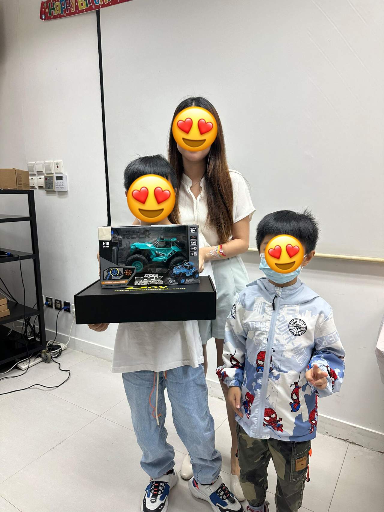 An adult poses with two children holding boxed gifts.