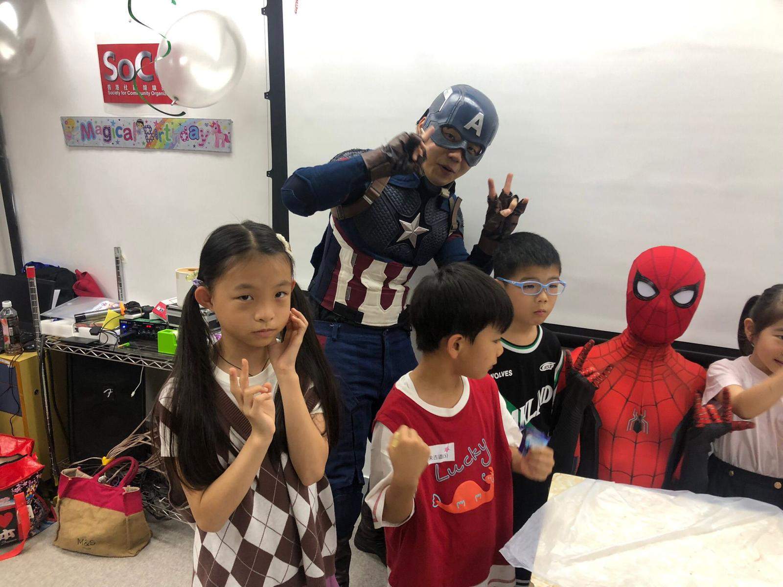 Children pose beside two costumed performers in the decorated room.