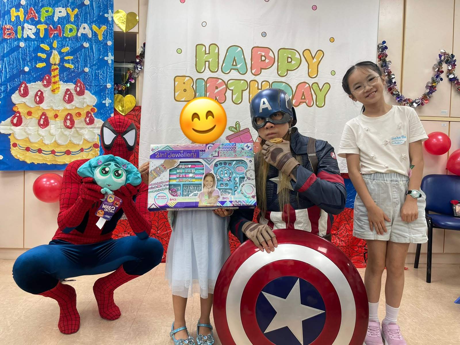 Costumed adults pose with two children displaying a large gift.
