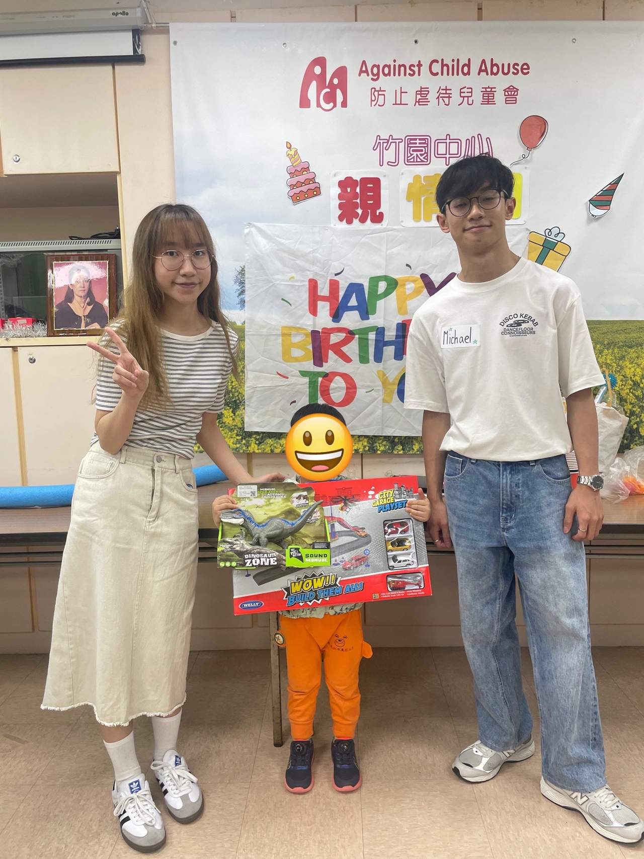 Two adults pose with a child holding several gifts.