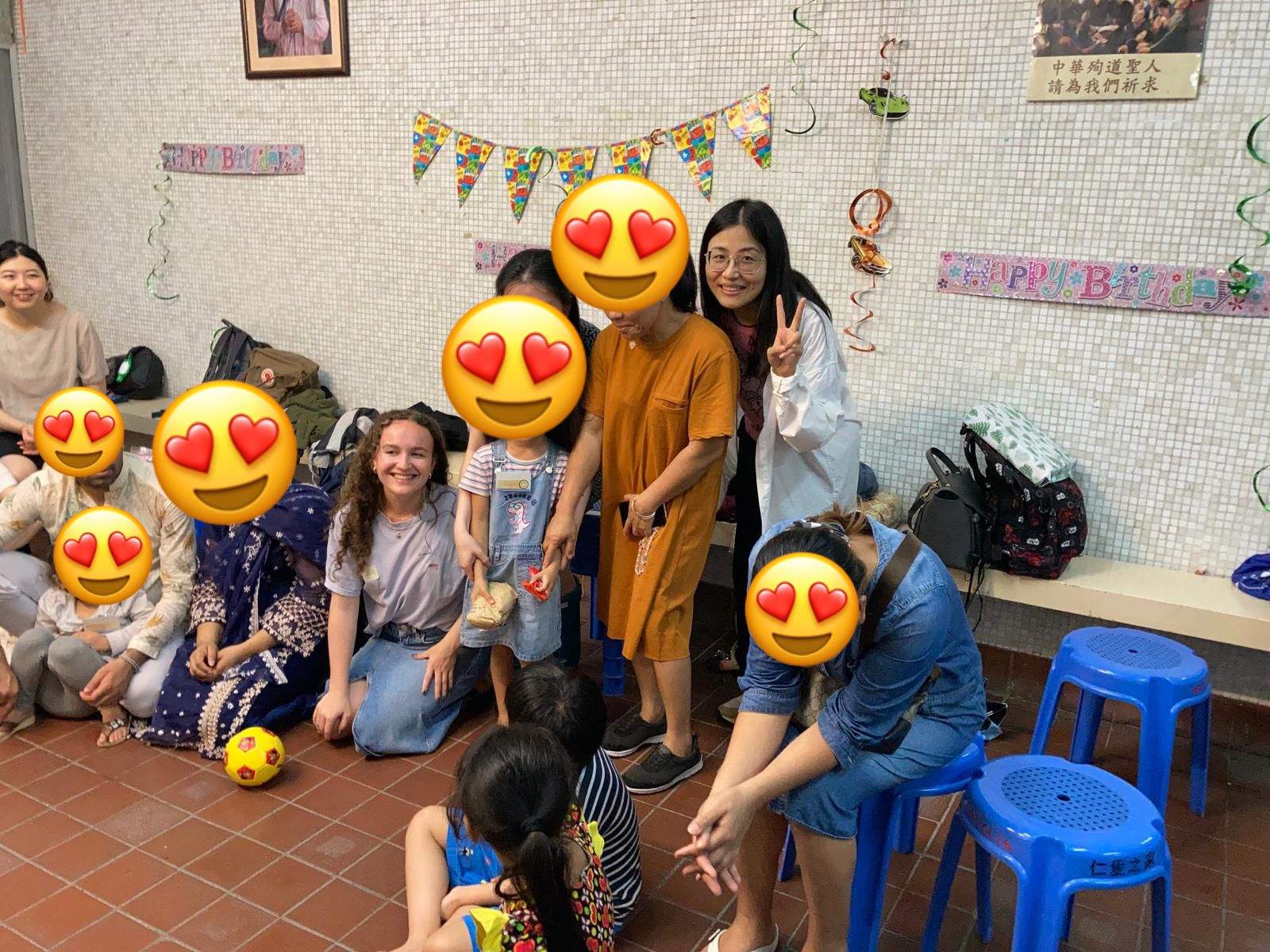 Adults and children gather beside a row of blue stools.