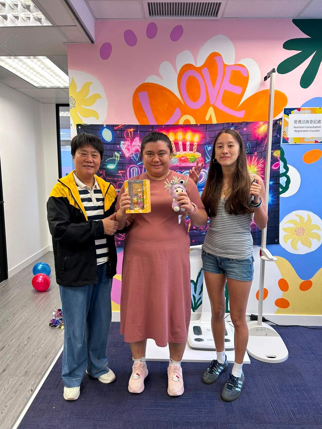Three people pose together while holding several small gifts.