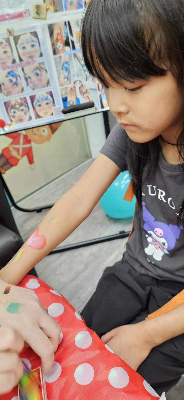 A child receives a painted design on their forearm.