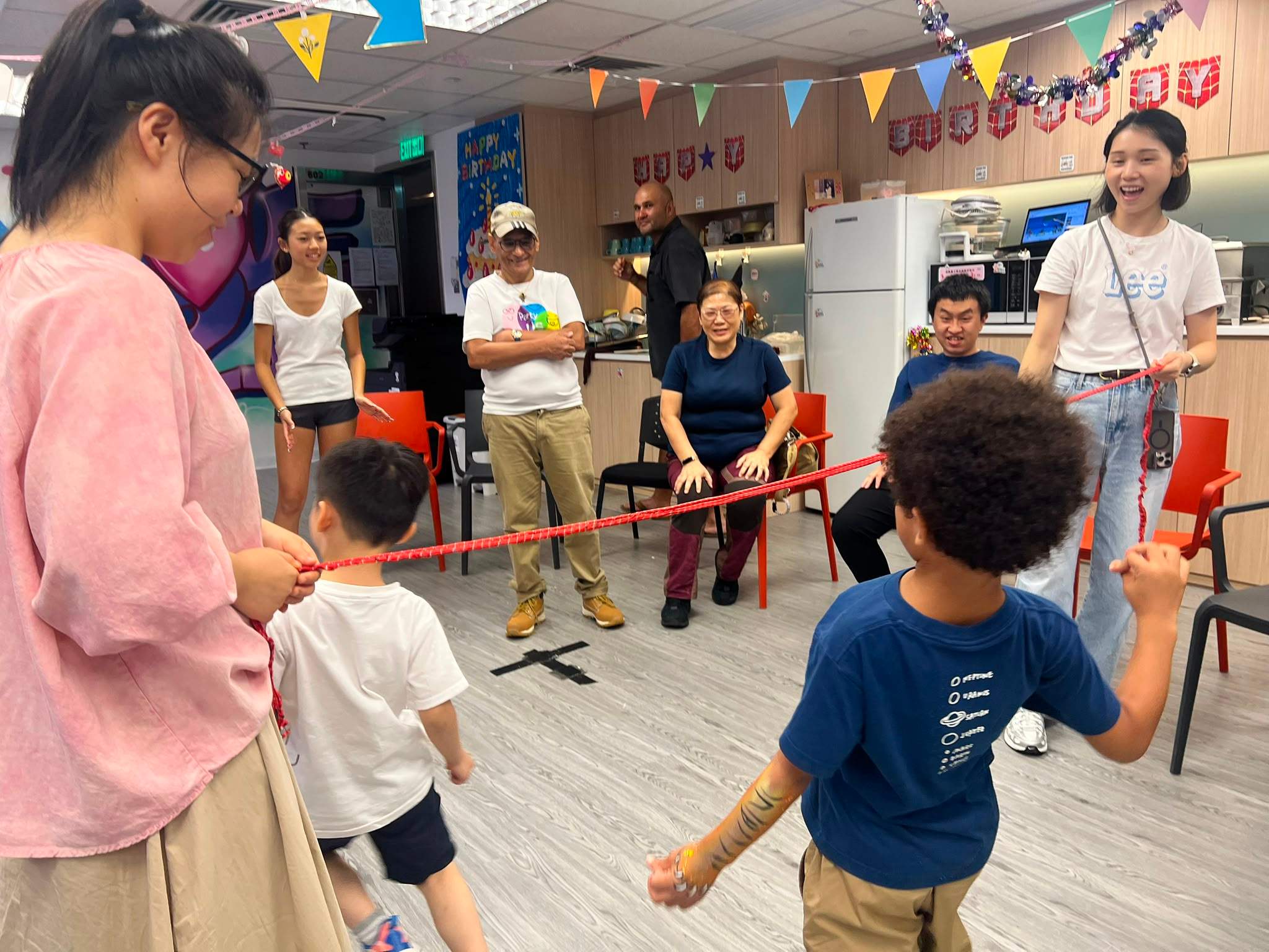 A child approaches a limbo bar held by two adults.