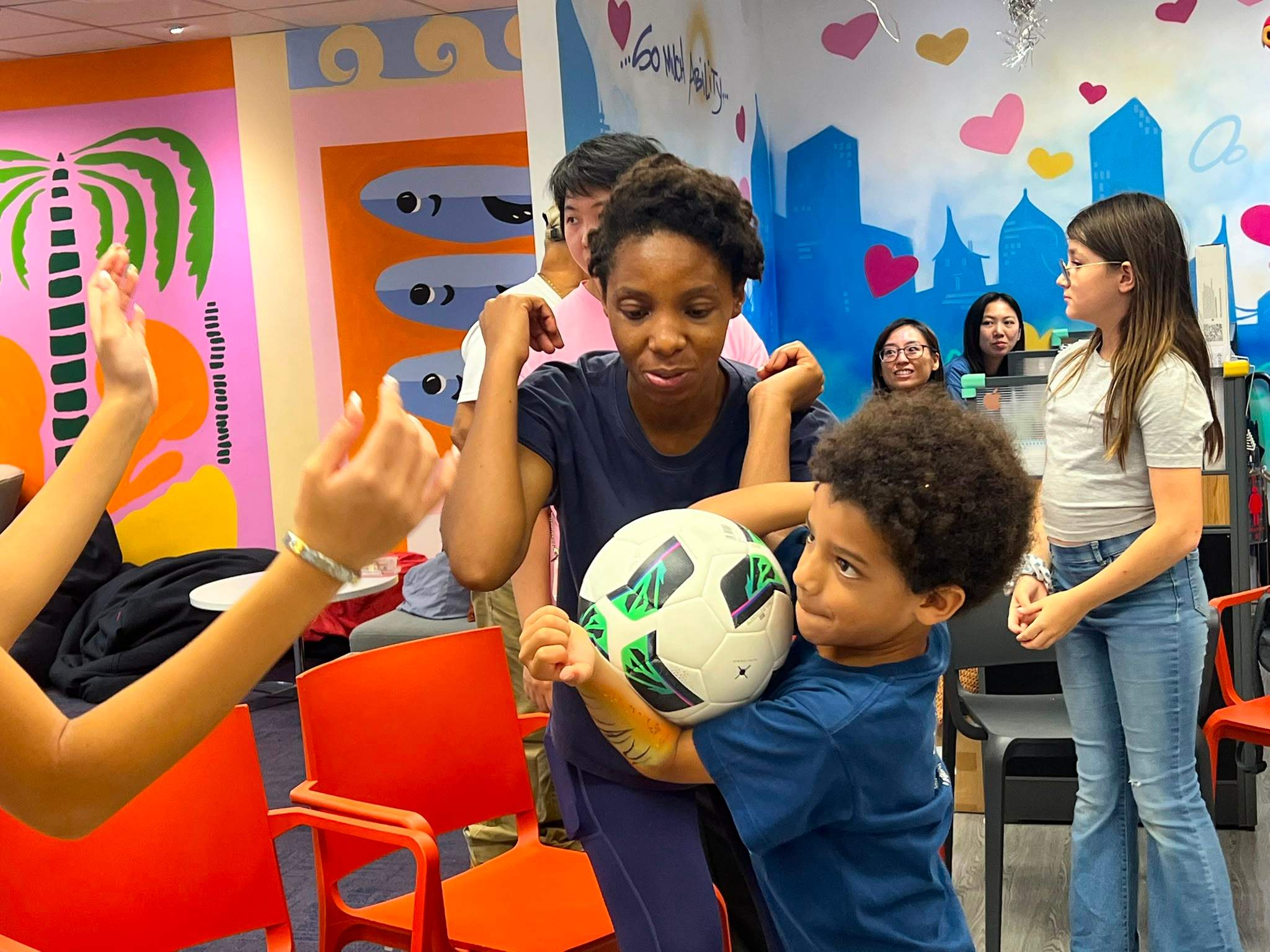 An adult and child hold a ball during a group game.