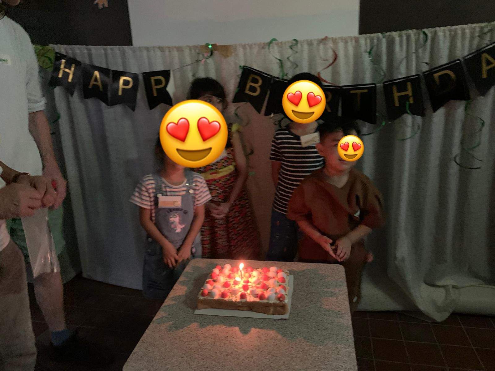Children stand behind a cake glowing with candles.