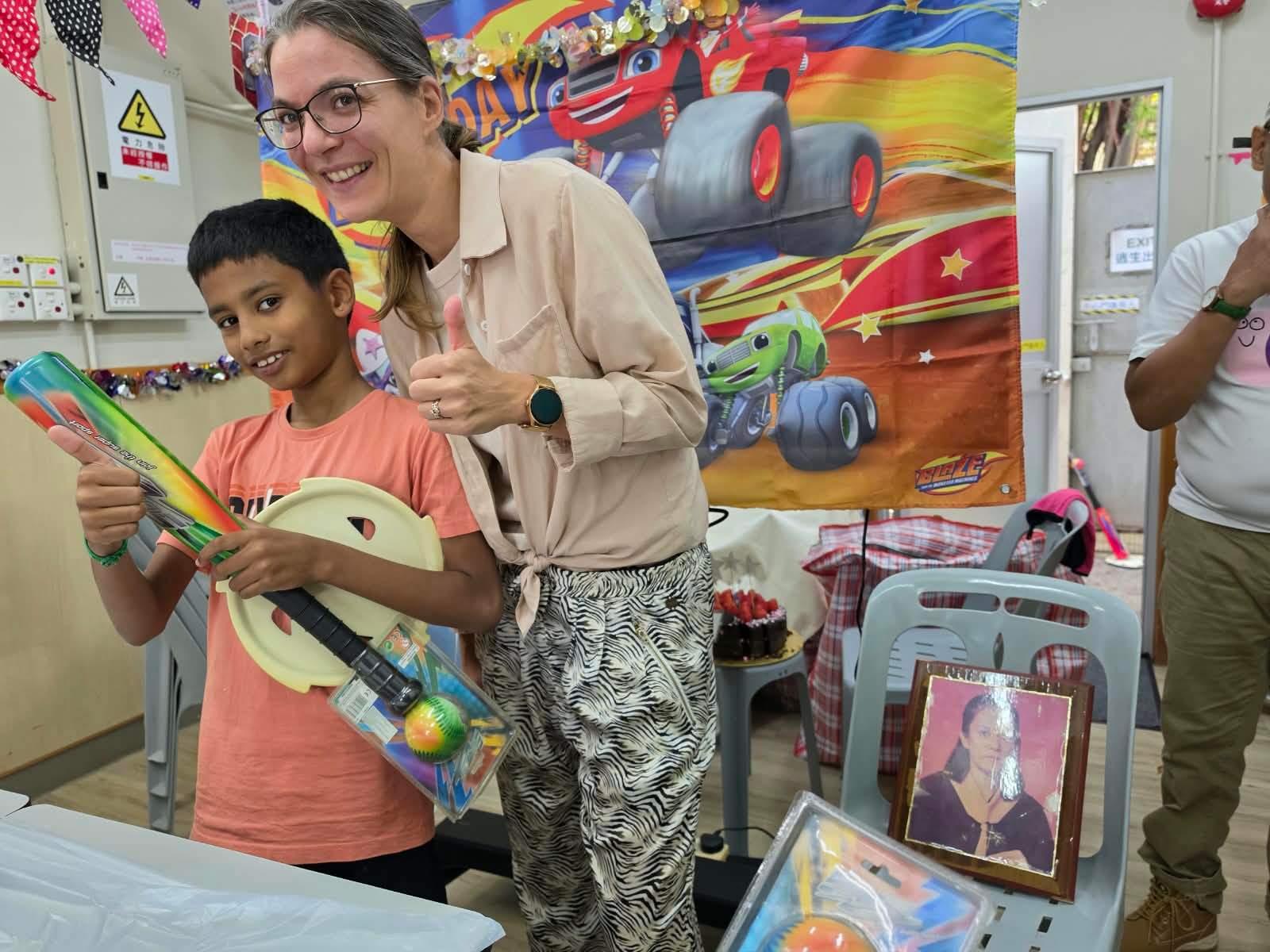 A volunteer poses with a child receiving a party gift.