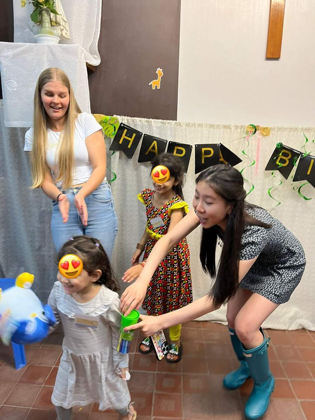 Adults assist a child during a balloon and party game.