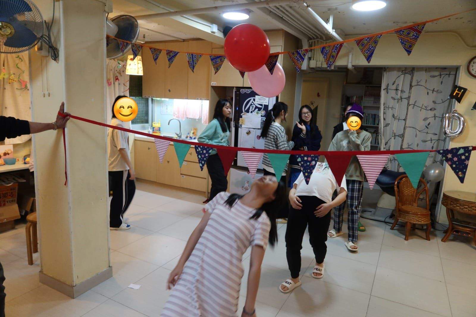 People play limbo beneath bunting in the decorated room.