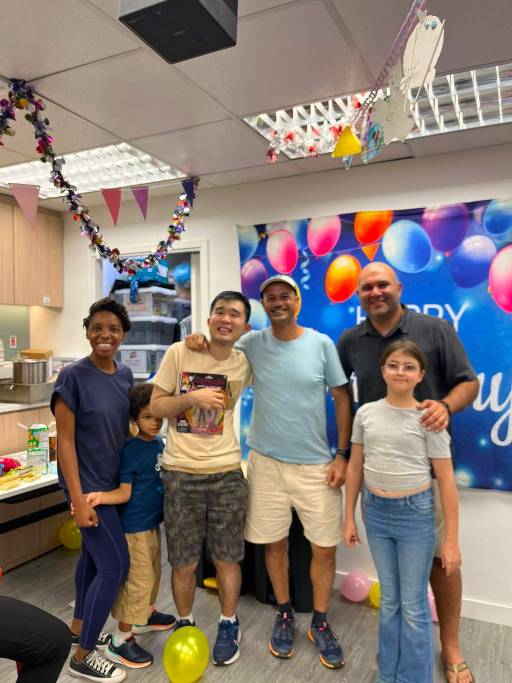 Five people stand together in front of a balloon backdrop.