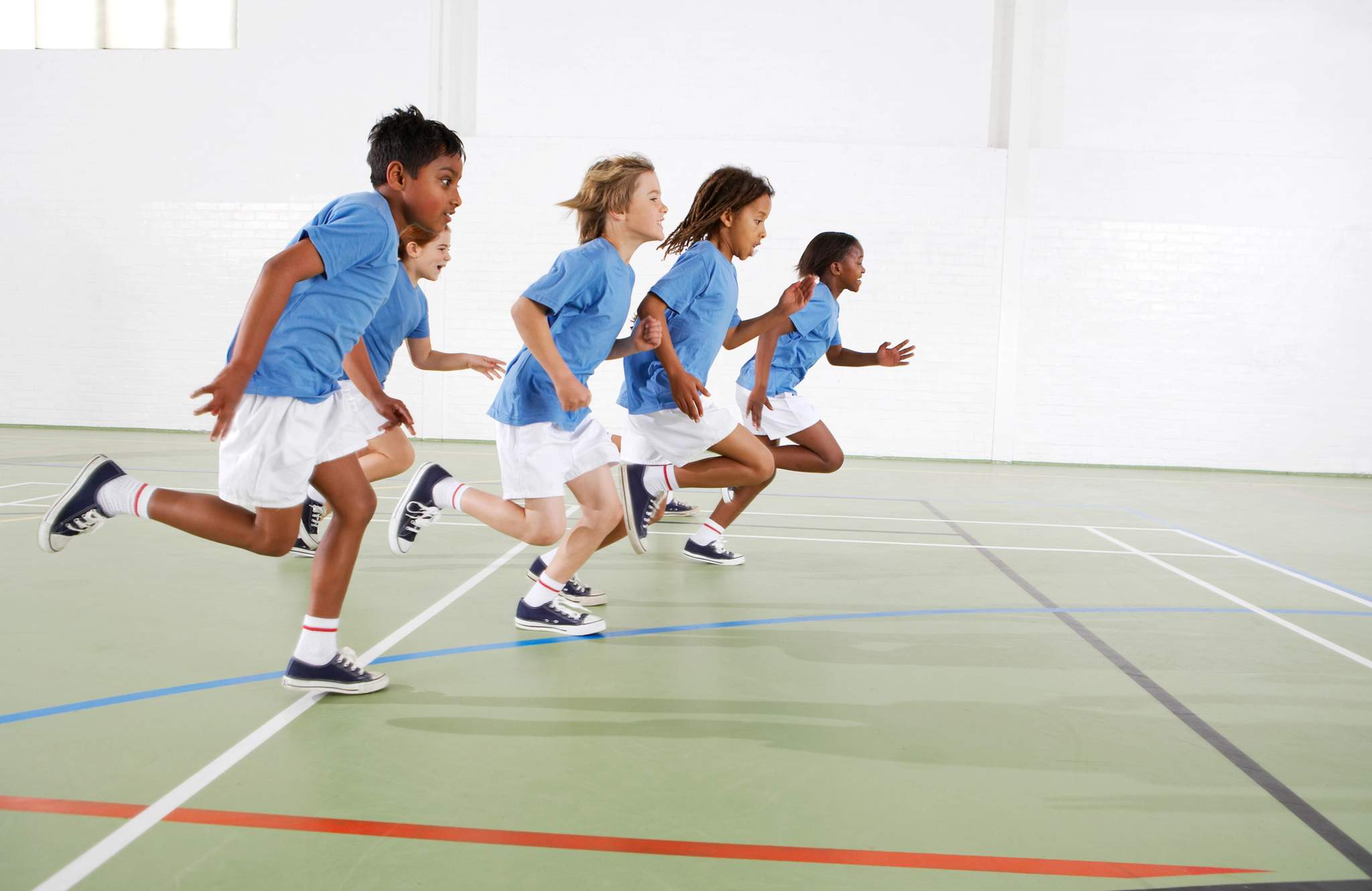 Children run together across a marked indoor court.
