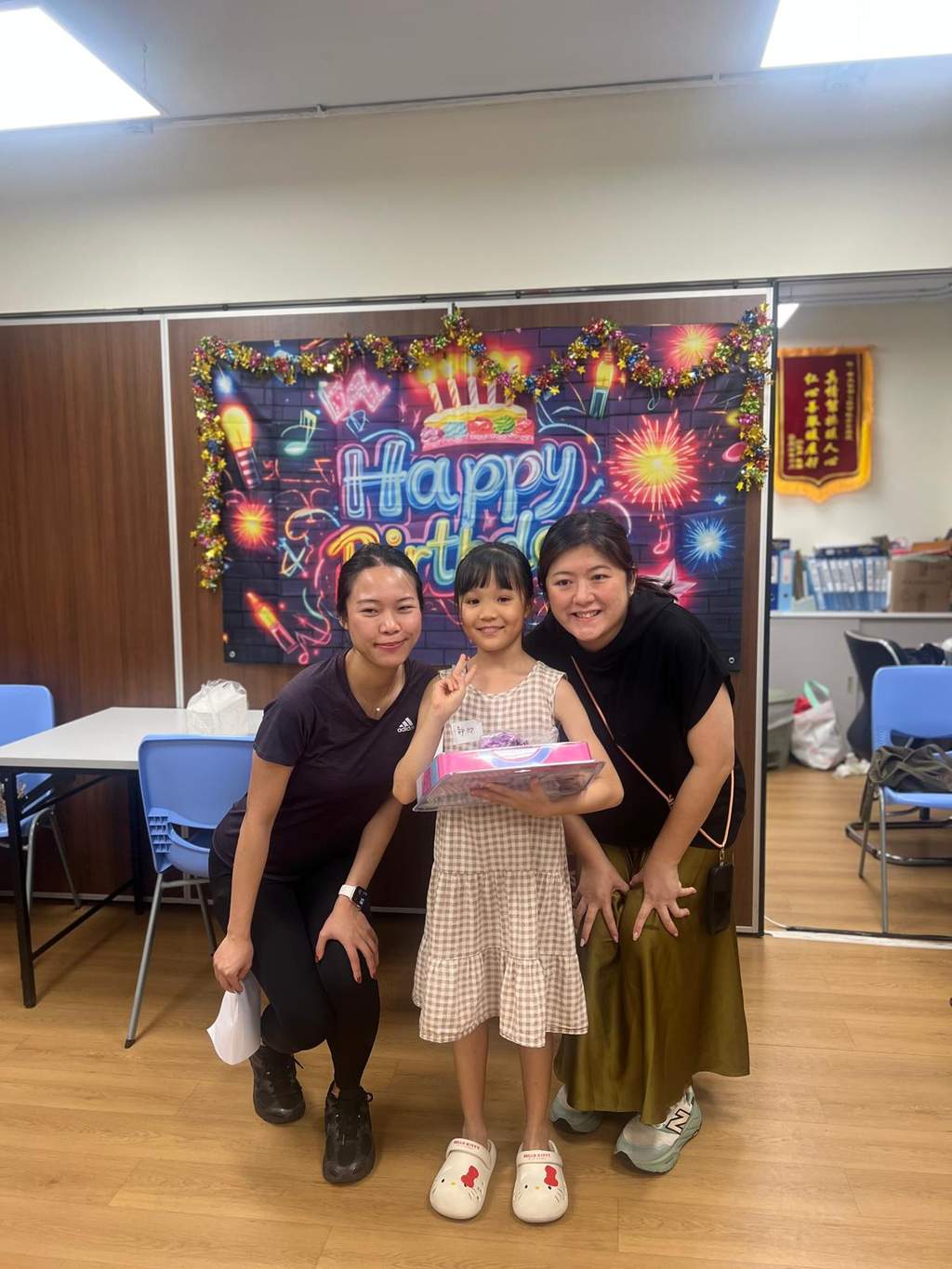 A child stands between two adults while holding a gift.