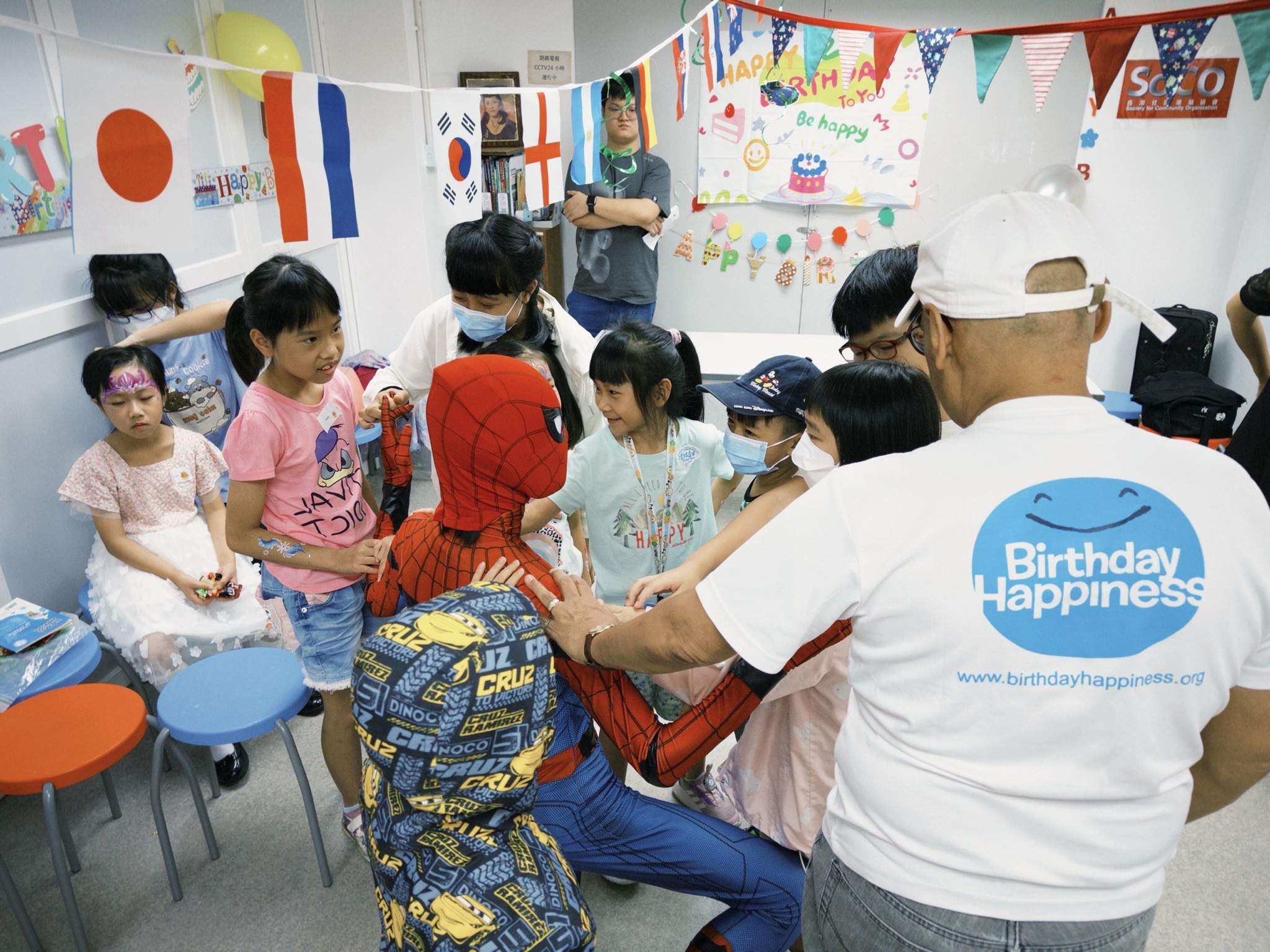 Adults and children gather around a face-painting activity.