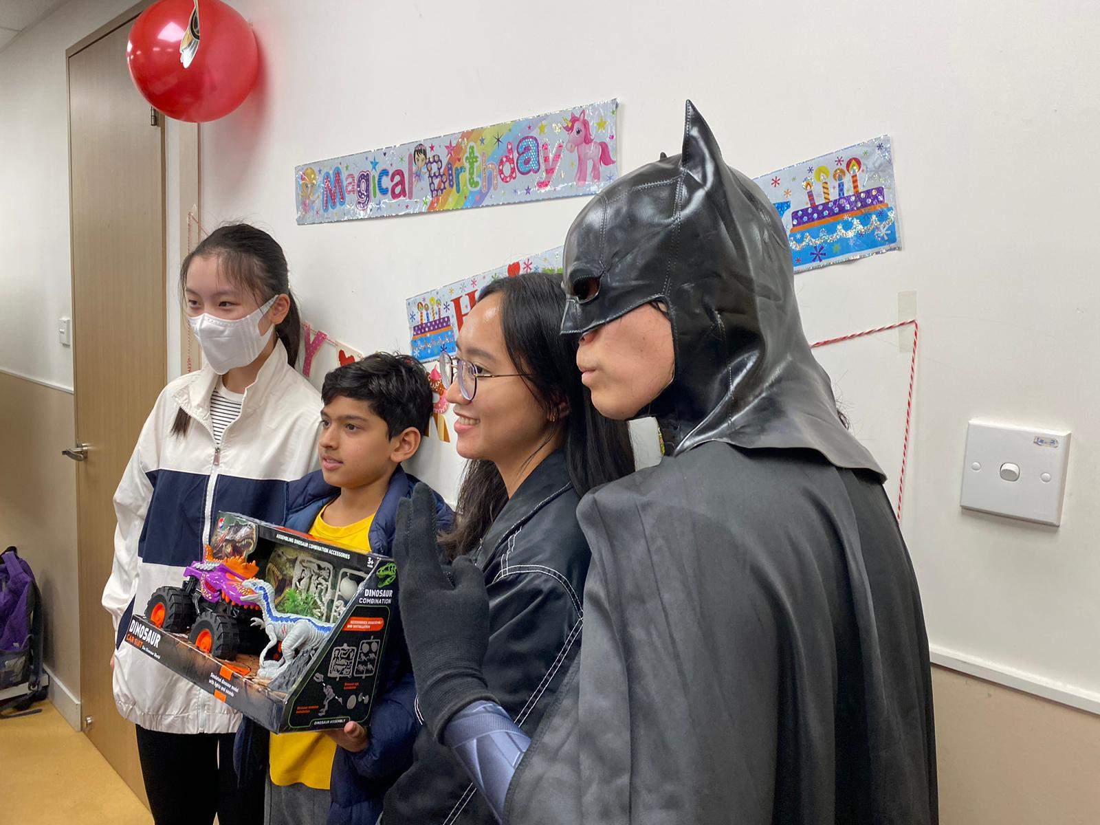 Adults and a costumed performer pose with a child holding gifts.