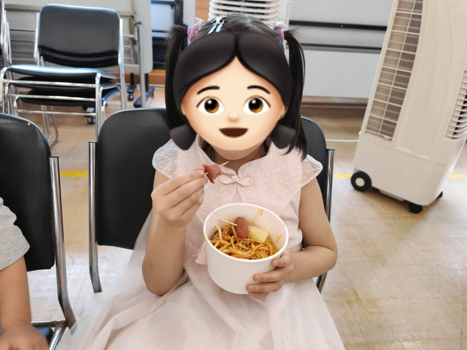 A child sits at a table with food and a drink.