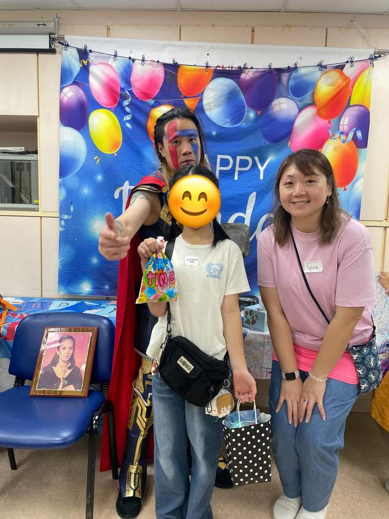 A costumed performer and adult pose with a child holding gifts.