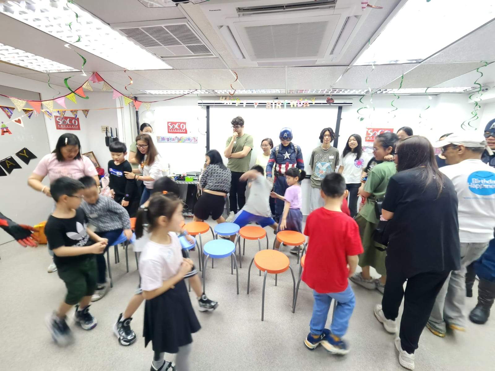 Adults and children move around during an indoor group game.