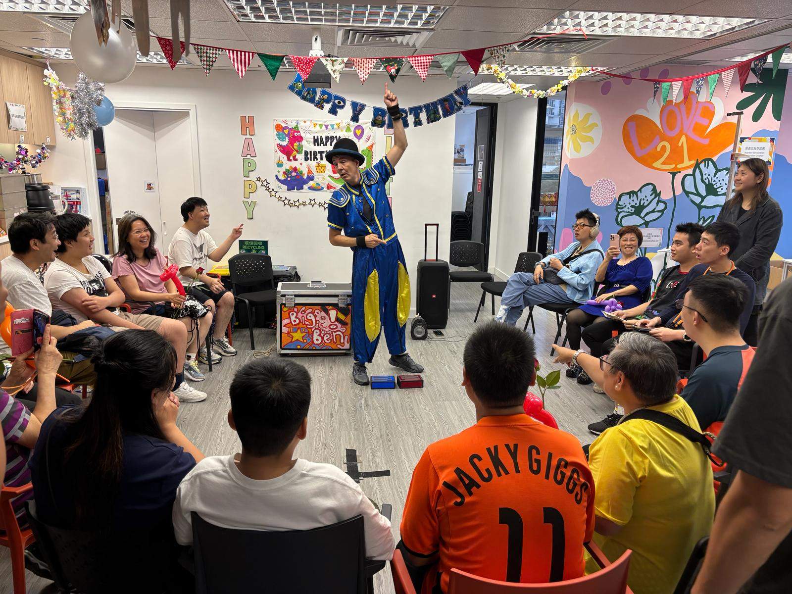 A performer presents an act to people seated in a semicircle.
