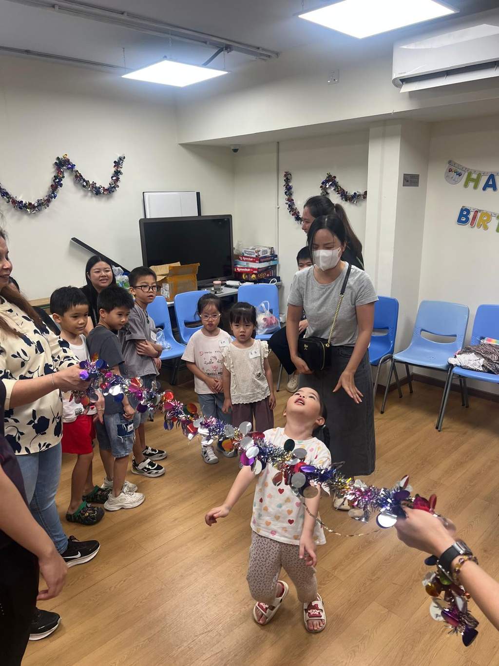 Children move through a tinsel hoop during an indoor game.